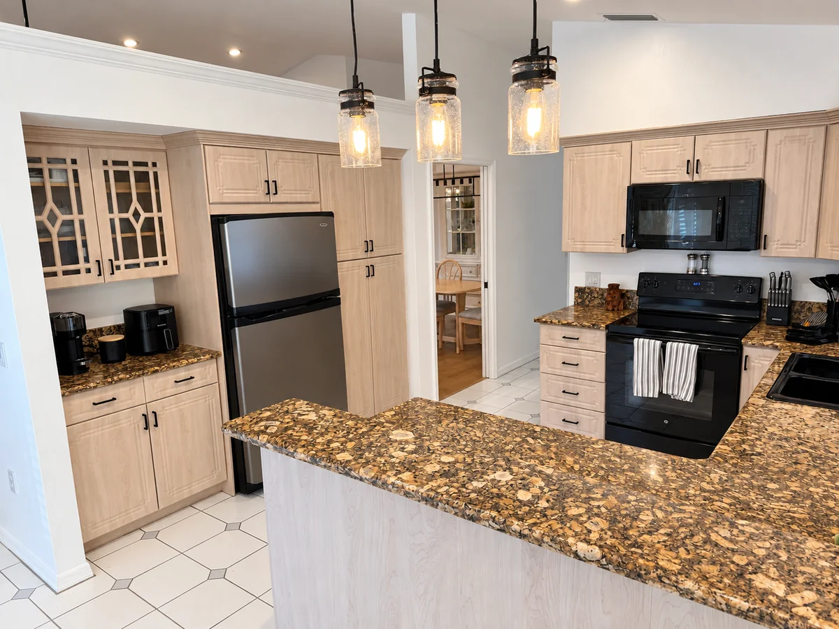 Kitchen refrigerator, stove, and microwave beside granite counters