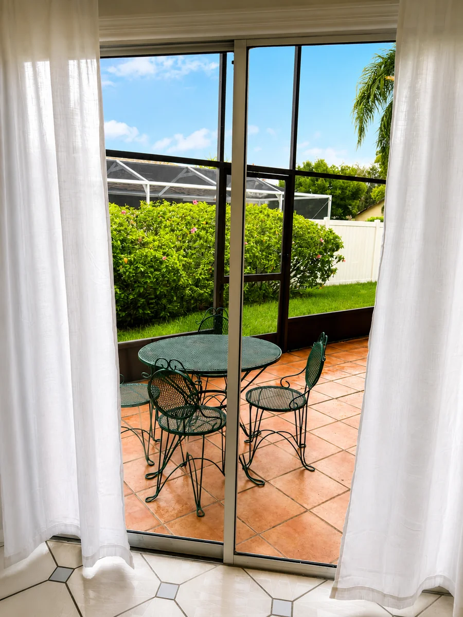 Screened porch with a round table and chairs, viewed through sliding glass doors